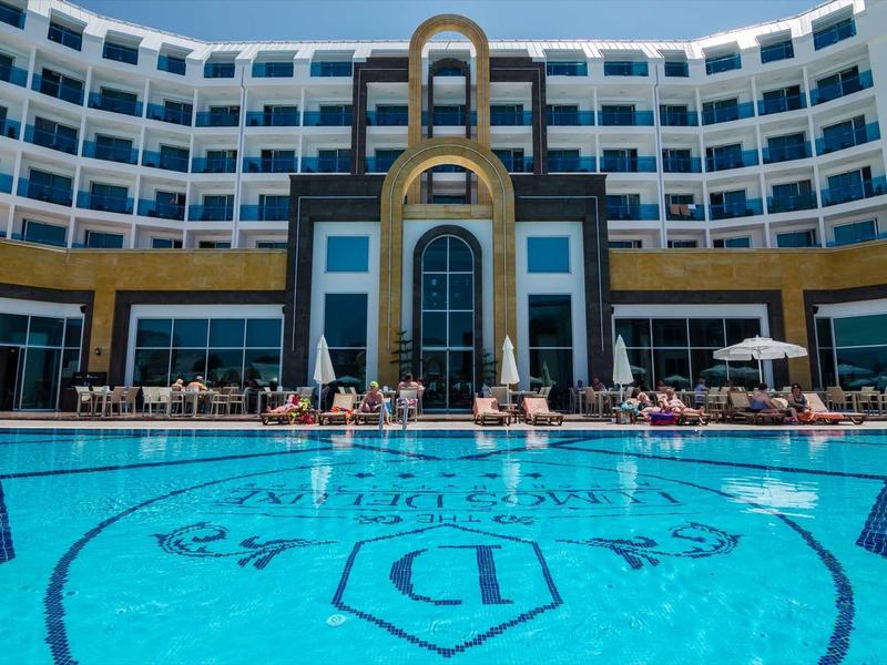 Moderní hotelový bazén s zakřivenou architekturou a lehátky za slunečného dne.