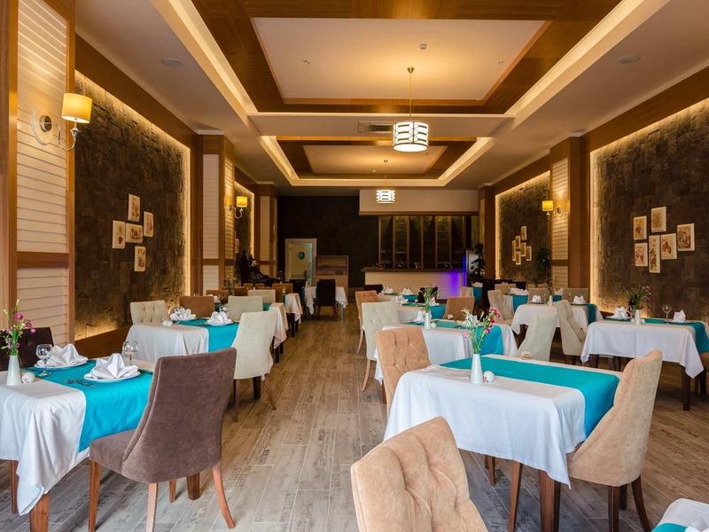 Elegantní restaurace s bílými ubrusy, modrými prvky a pohodlnými židlemi za teplého osvětlení.