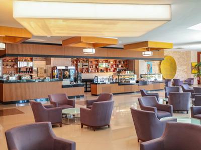Moderner Hotelbarbereich mit vielen violetten Sesseln, Tischen und breiter, gut bestückter Bar.