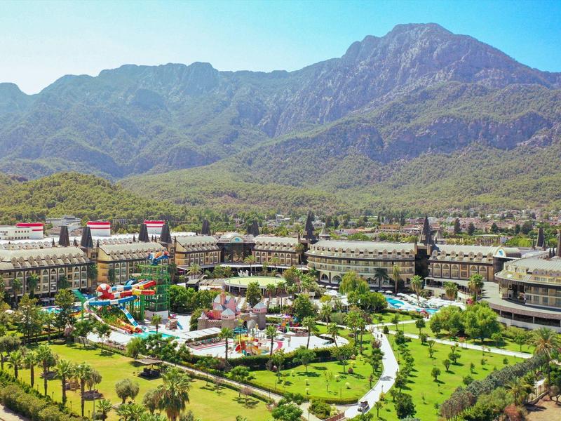 Gran complejo hotelero con jardín y montañas al fondo bajo un cielo despejado.