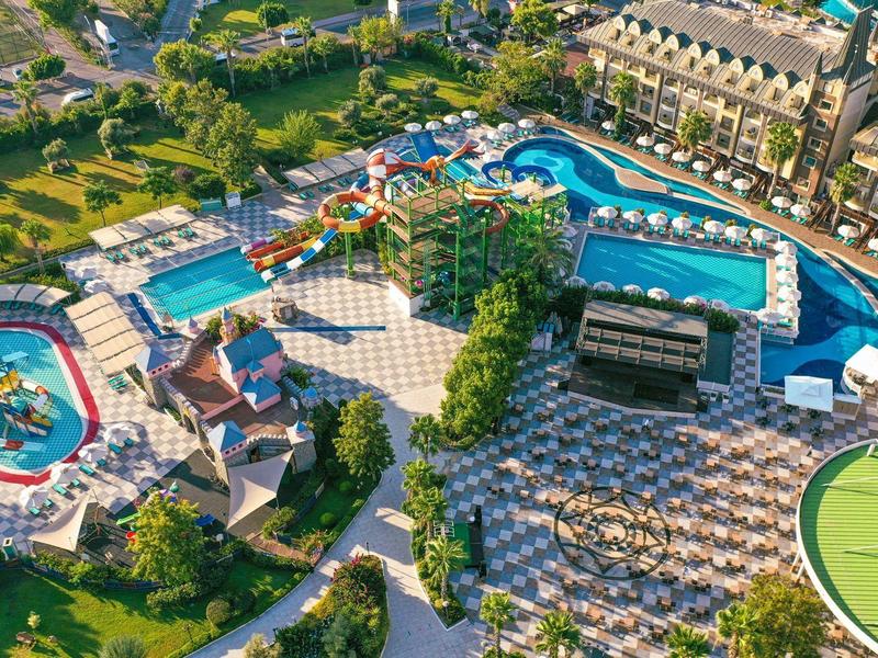 Vista amplia de un resort con varias piscinas, tumbonas y áreas verdes.