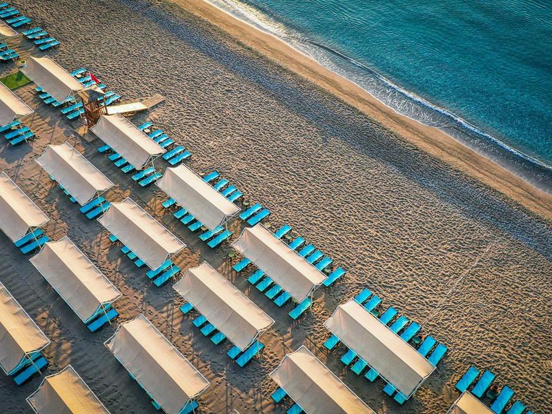 Vista aérea de filas ordenadas de tumbonas azules en la playa junto al mar