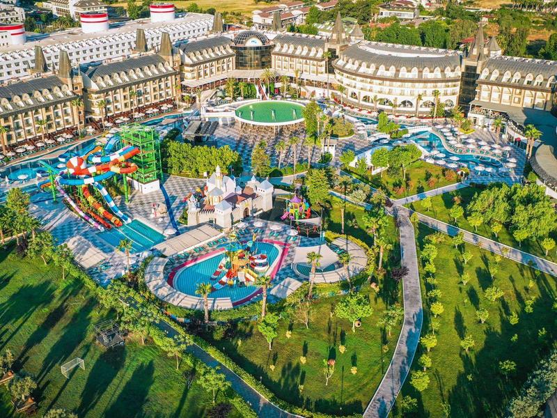 Gran parque acuático con toboganes y piscinas, rodeado de edificios y mucha vegetación.