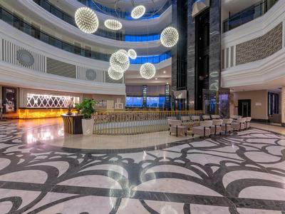 Prostorná elegantní hotelová lobby s kulatými závěsnými světly a vzorovanou podlahou.