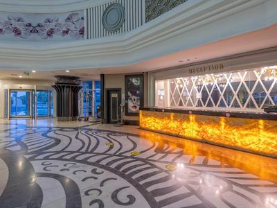 Elegantní hotelová lobby s uměleckou mramorovou podlahou a osvětlenou recepcí.