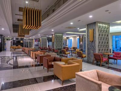 Prostorná hotelová hala s pohodlnými křesly, mramorovou podlahou a moderním osvětlením.