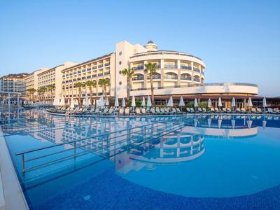 Velký hotel u bazénu s jasně modrou oblohou v pozadí.