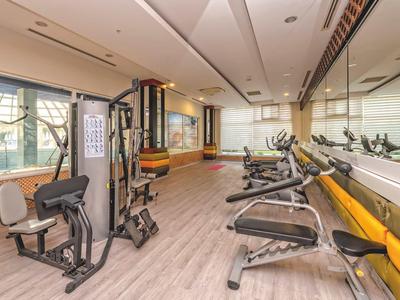 Nowoczesna siłownia z różnymi urządzeniami do ćwiczeń i dużymi lustrami na ścianie.