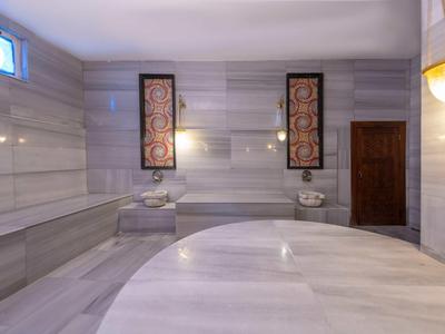 Elegantní turecký hammam s mramorovými zdmi a centrální kulatou plochou na ležení.