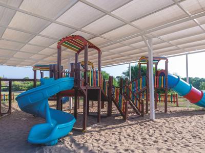Krytý dětský koutek s barevnými skluzavkami a pískovým povrchem za slunečného počasí.