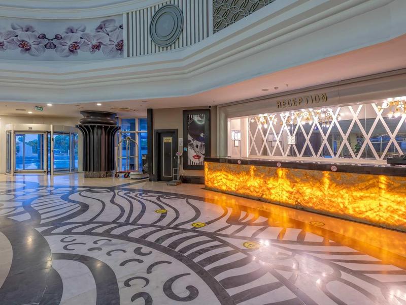 Elegantní hotelová lobby s uměleckou mramorovou podlahou a osvětlenou recepcí.