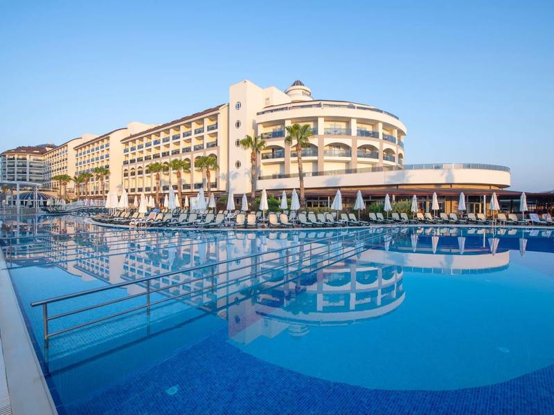 Velký hotel u bazénu s jasně modrou oblohou v pozadí.