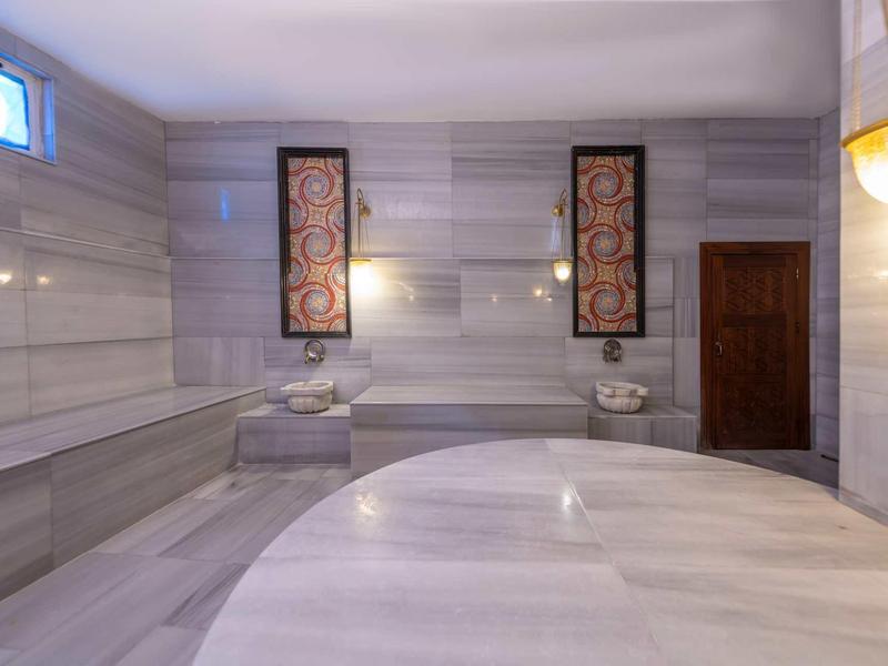 Elegantní turecký hammam s mramorovými zdmi a centrální kulatou plochou na ležení.