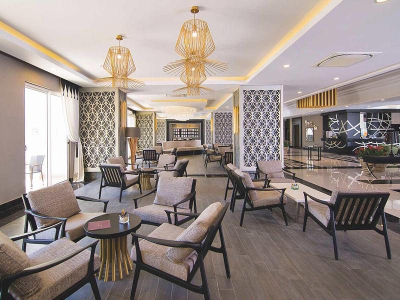 Elegantní, moderní hotelová lounge s křesly a stylovými závěsnými světly.