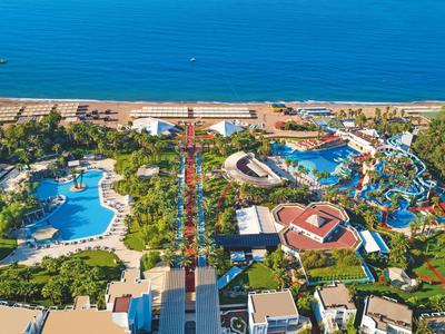 Große Wasserpark-Anlage mit Pools, Rutschen, Grünflächen und Meer im Hintergrund.