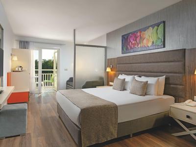 Světý hotelový pokoj s velkou postelí, balkonem a moderním vybavením.