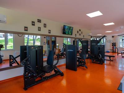 Světle hotelové fitness s moderním vybavením a oranžovou podlahou.