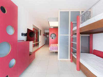 Modernes Schlafzimmer mit weißen Etagenbetten, roten Wänden und einem offenen Raumdesign.