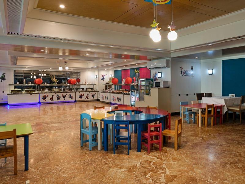 Barevné dětské stoly a židle v prostorné, moderní jídelně s bufetovým pultem.