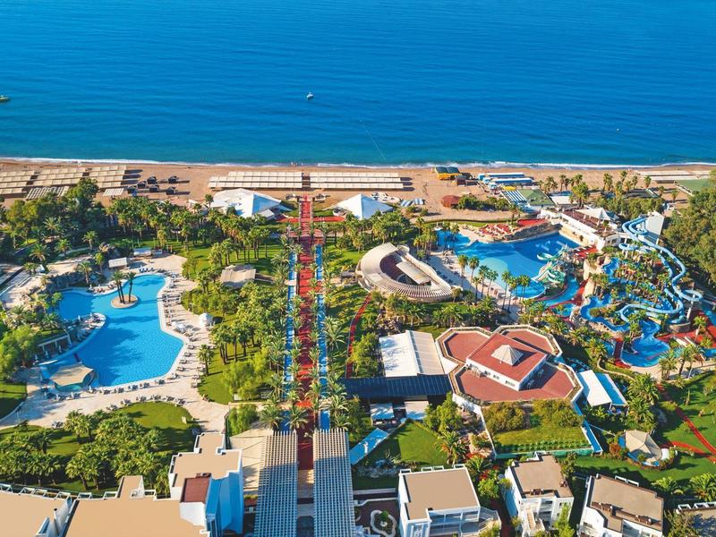 Letecký pohled na velký přímořský vodní park s bazény, skluzavkami a zelení.