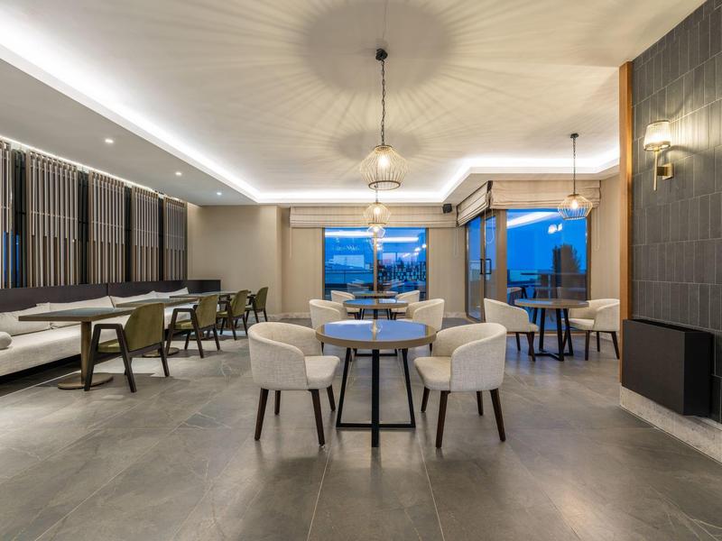 Sala de restaurante moderna y espaciosa con sillas acolchonadas y vista a través de ventanas grandes al mar.