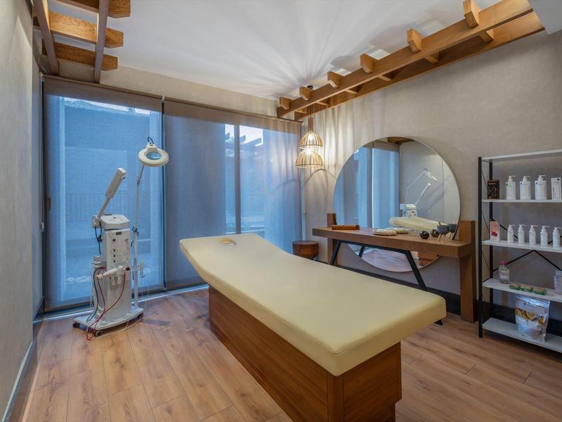 Sala de tratamiento moderna con camilla, equipos cosméticos y suelo de madera