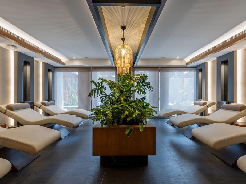 Sala de descanso moderna con tumbonas y planta central en un hotel.