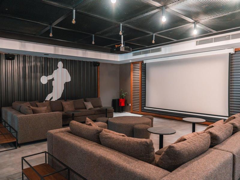 Área de salón de hotel acogedora con sofás marrones, mesas y iluminación moderna.