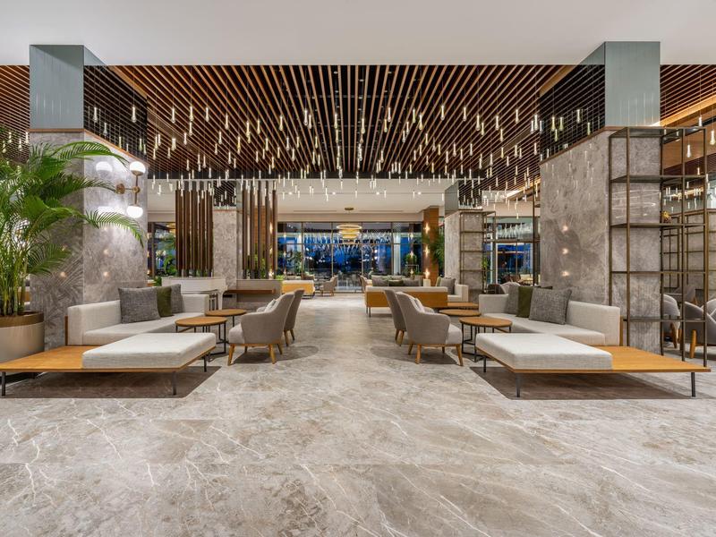 Lobby moderna de hotel con asientos cómodos, detalles de madera y espacio amplio.
