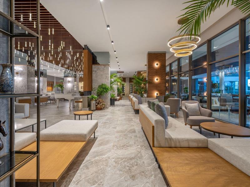 Interior moderno del vestíbulo del hotel con muebles elegantes, plantas y grandes ventanales.