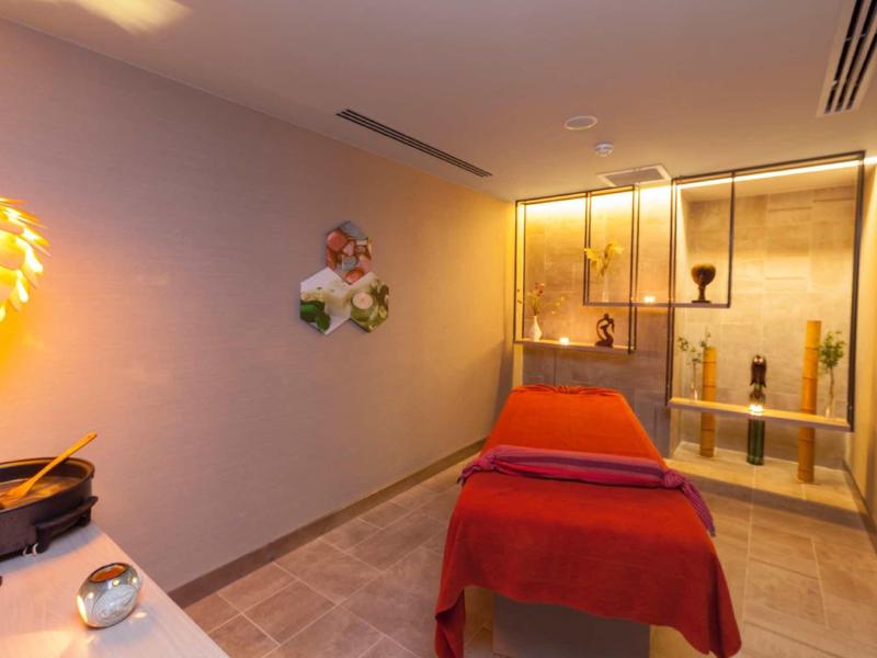 Cozy treatment room with red bed and soft lighting in a wellness hotel.