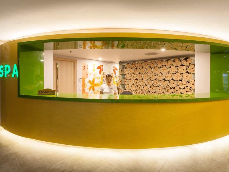 Reception desk in a spa with bright lighting and green accents.