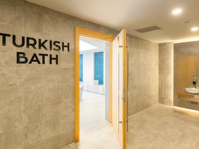 Bright, modern Turkish bath area with beige tiles and open entrance.