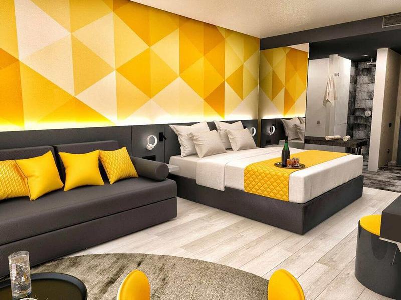 Modern hotel room with yellow geometric accents and cozy double bed.