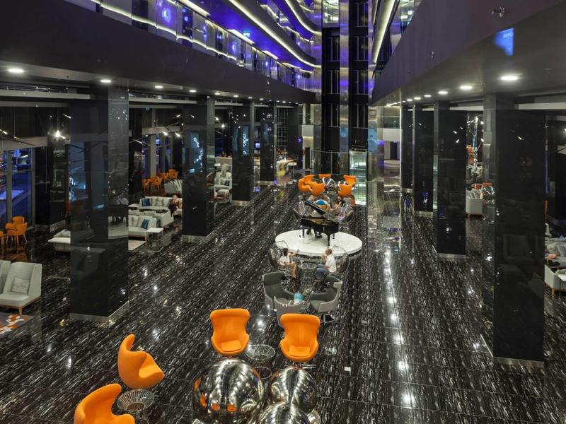 Modern hotel lobby with shiny black floor, colorful seating, and mirrored walls.