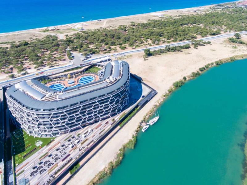 Modern hotel complex by the river with beach and sea in the background under clear skies.