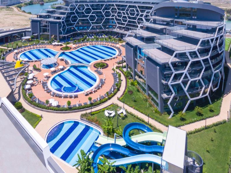 Modern hotel with several blue swimming pools and water slides in a spacious complex.
