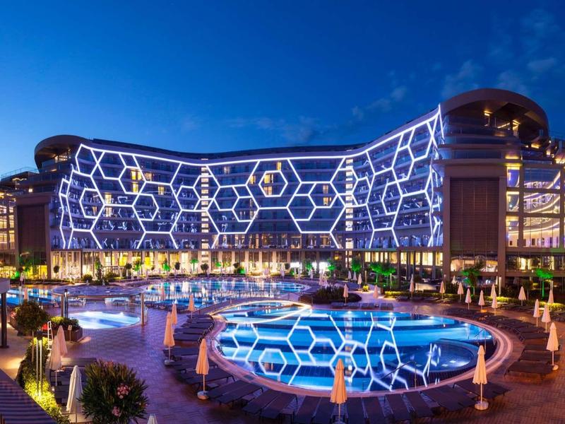 Modern hotel with unique geometric lighting and illuminated pool at dusk