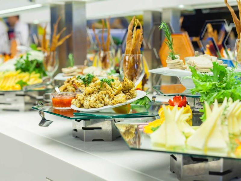 Buffet with various hot and cold dishes on a long counter in the hotel.