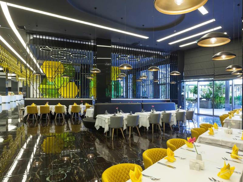 Modern restaurant with black marble floor, yellow chair cushions, and large windows.
