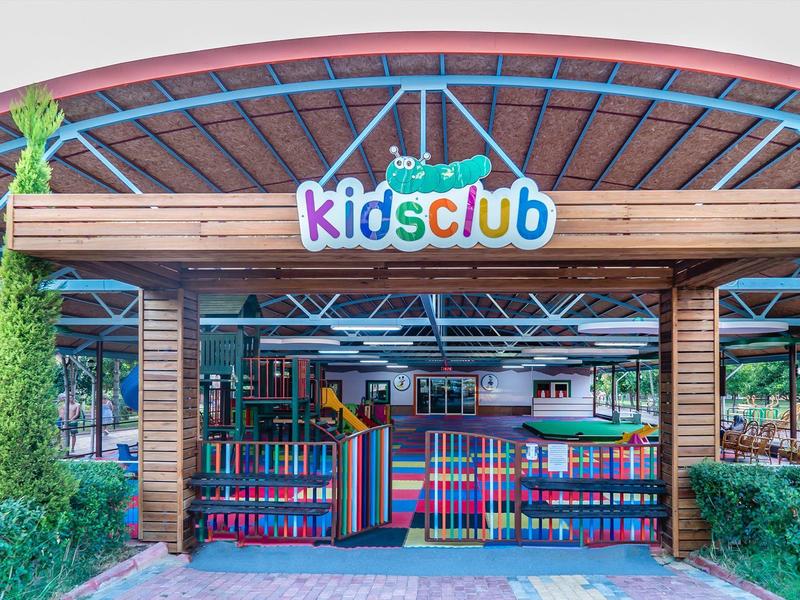 Colorful kids club entrance under a wooden roof in a holiday resort.