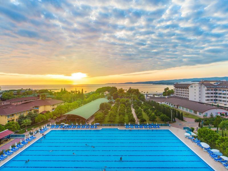 Large swimming pool with blue water lanes at sunset overlooking sea and buildings.
