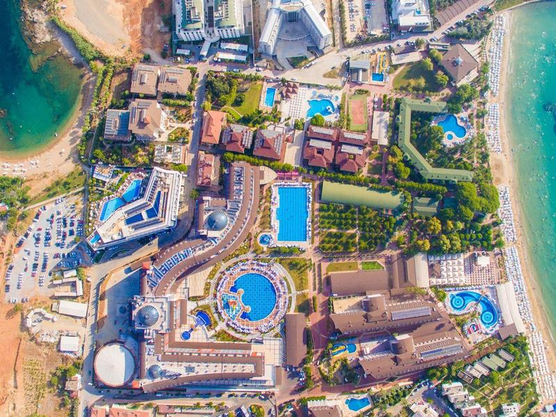 Aerial view of a large resort with multiple pools next to a sandy beach and turquoise sea.