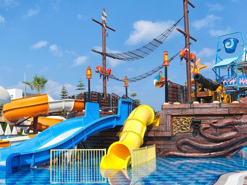 Colorful water slide and pirate ship in amusement park under clear sky