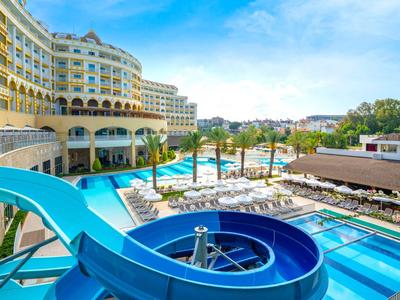 Hotel with water park, blue water slide, pool area, and sun loungers under a blue sky.