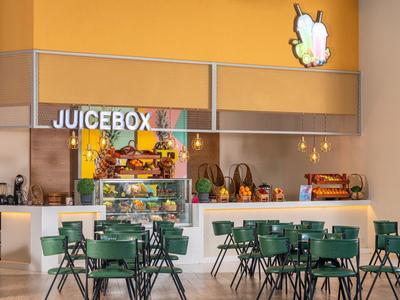 Moderne sapbar genaamd Juicebox met groene stoelen en tafels in lichte omgeving