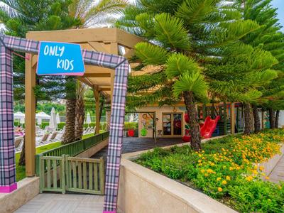 Ingang naar een speelruimte voor kinderen met een blauw bordje 'Only Kids', omgeven door bomen en bloemen.