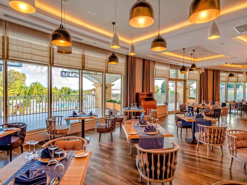 Modern restaurant met houten vloeren, grote ramen en stijlvolle eettafels.