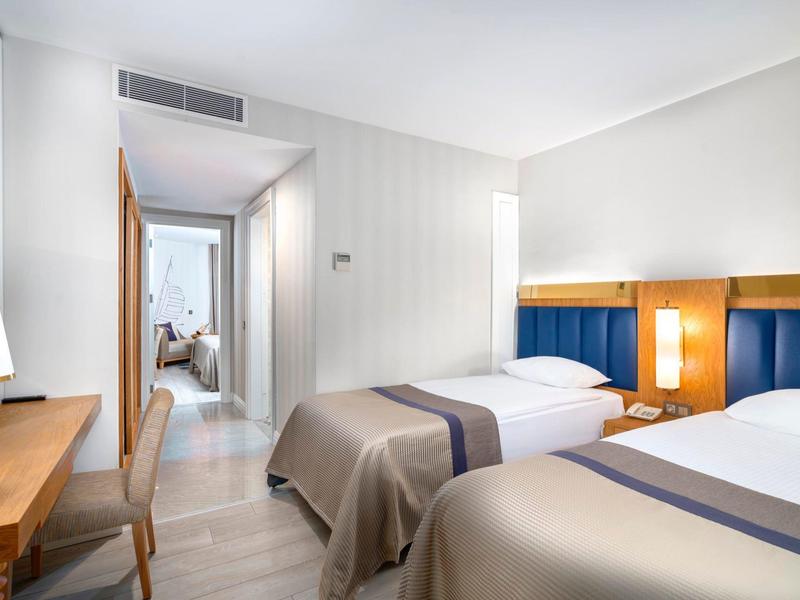 Hotelkamer met twee eenpersoonsbedden, modern meubilair en neutrale kleuren.