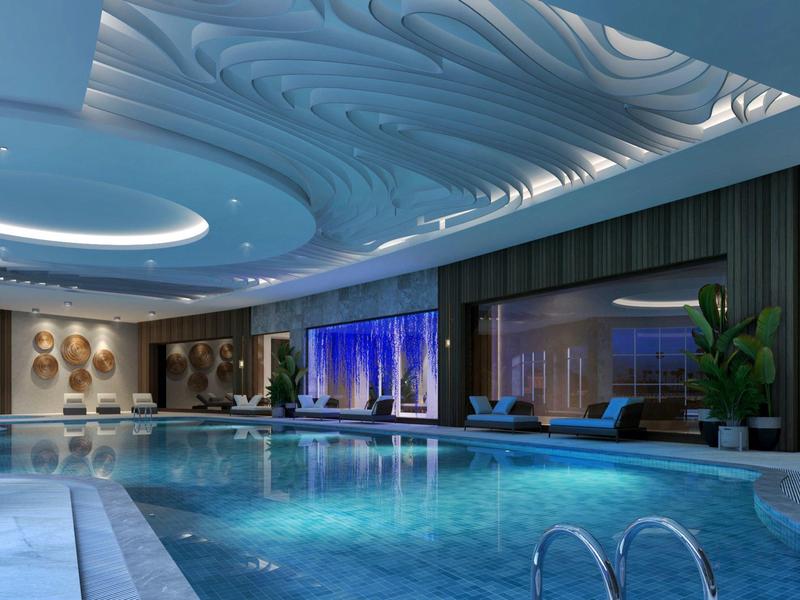 Modern binnenzwembad met golfvormig plafond en rustgevende zitgedeeltes.